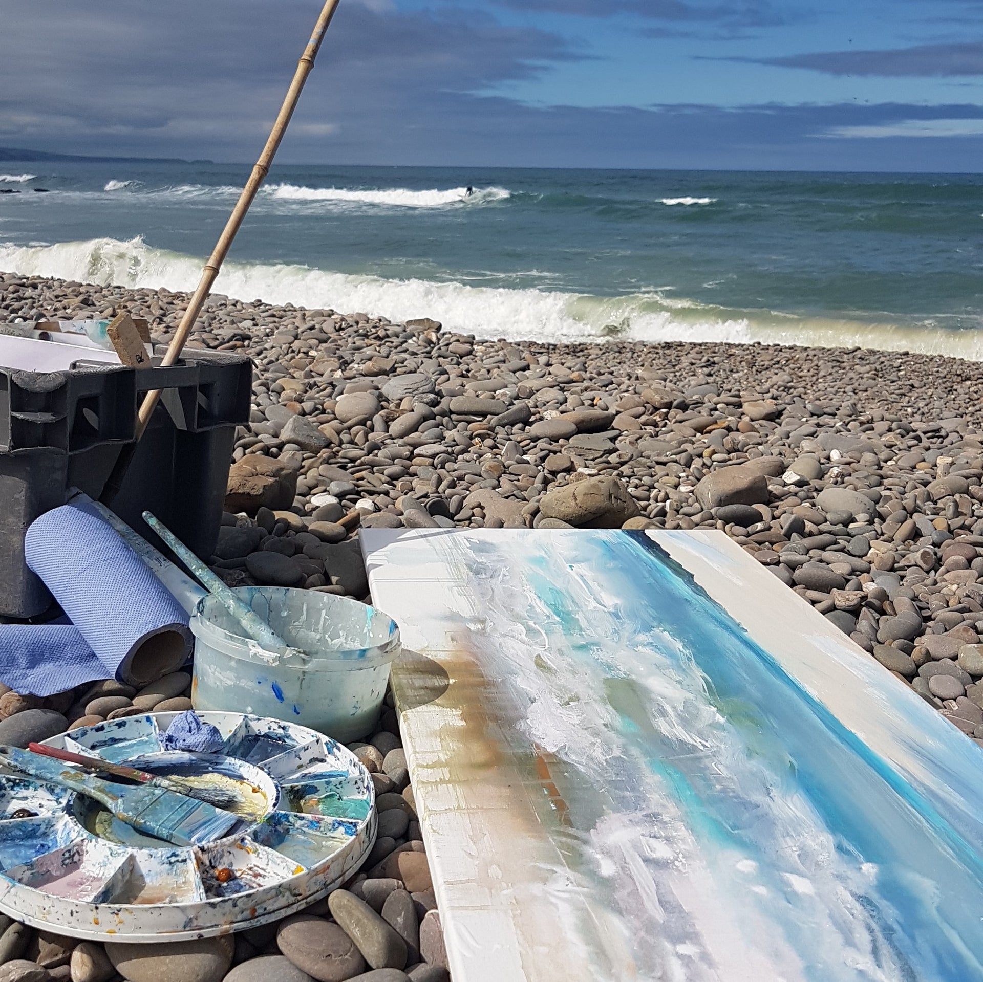 Plein air painting at Northcott mouth with a canvas on the stones