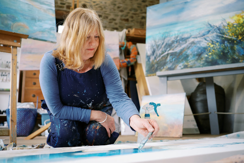 Bude artist on the floor painting a large seascape